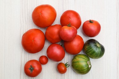 Photo of Many different ripe tomatoes on white wooden table, flat lay