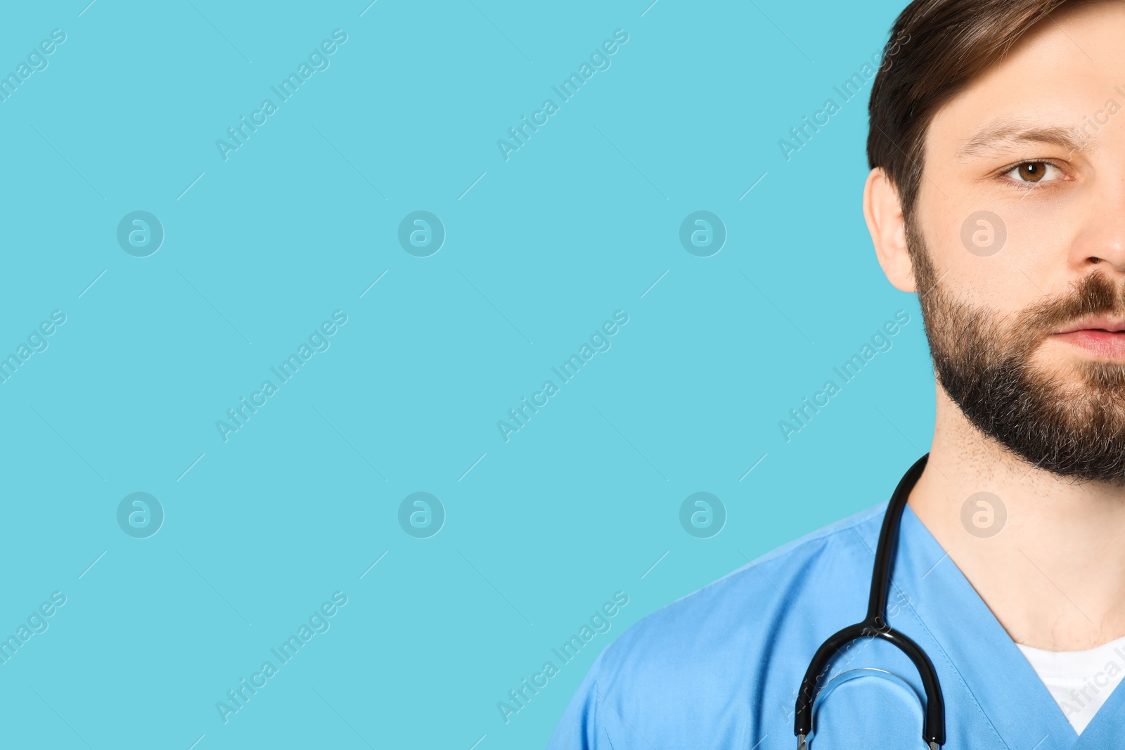 Photo of Doctor or medical assistant (male nurse) in uniform with stethoscope on turquoise background, closeup. Space for text