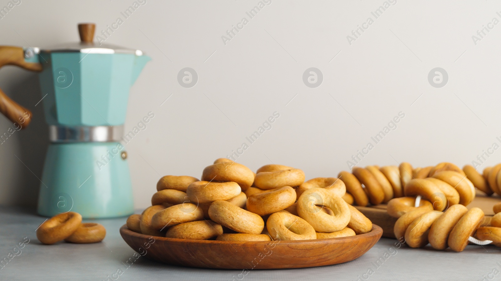 Photo of Plate with delicious ring shaped Sushki (dry bagels) on light grey table. Space for text