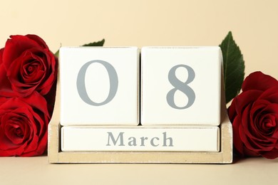 Photo of Wooden block calendar with date 8th of March and roses on beige background. International Women's Day