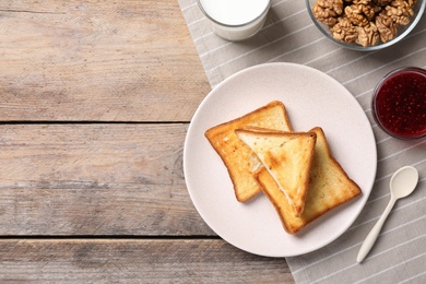 Breakfast with toasts, jam and glass of milk on wooden table, flat lay. Space for text