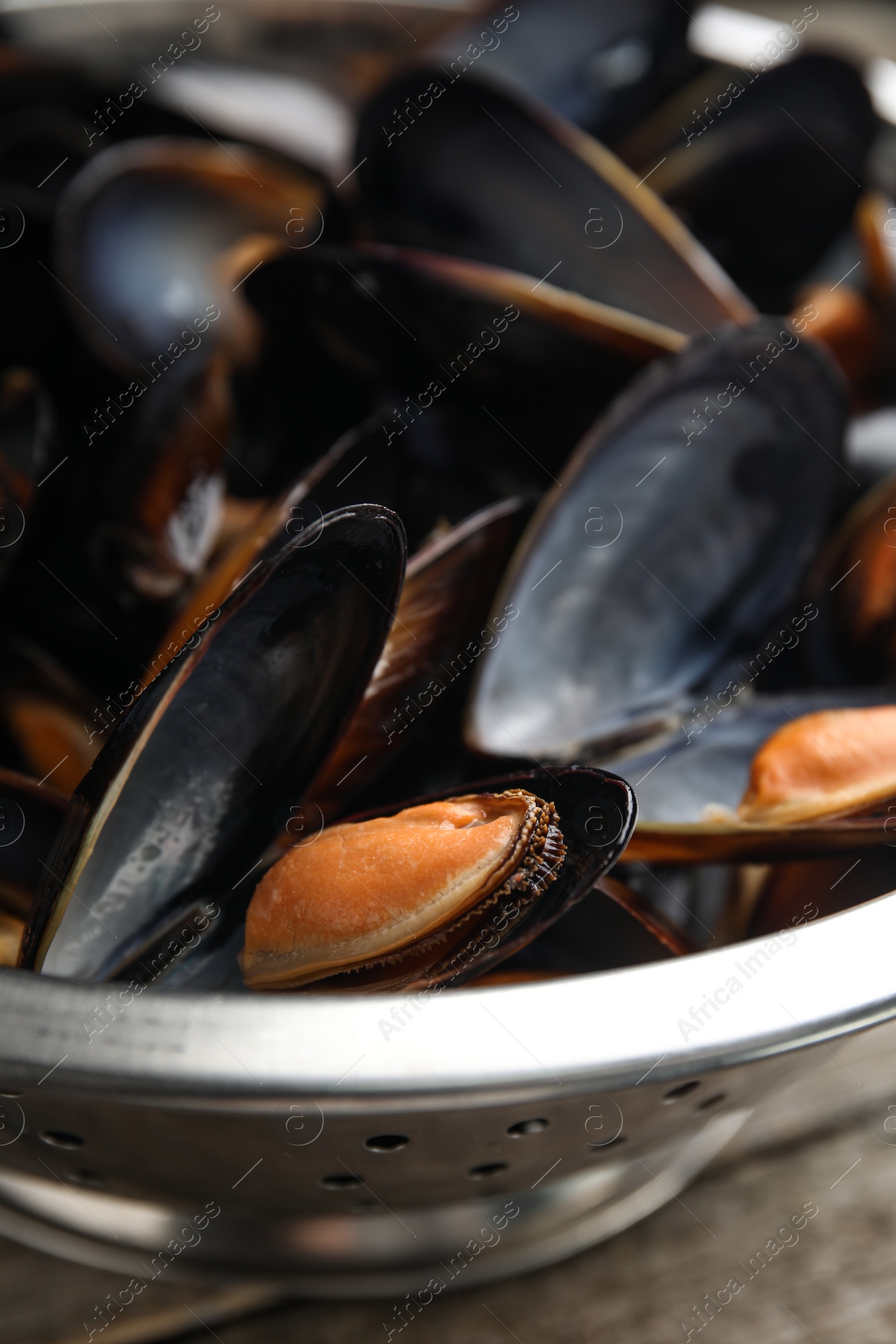 Photo of Colander with delicious cooked mussels, closeup view