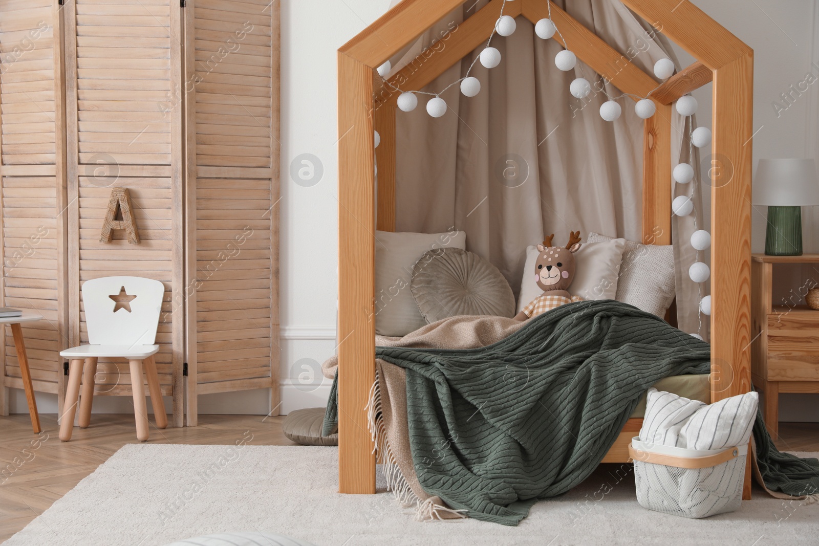 Photo of Stylish child room interior with wooden house bed