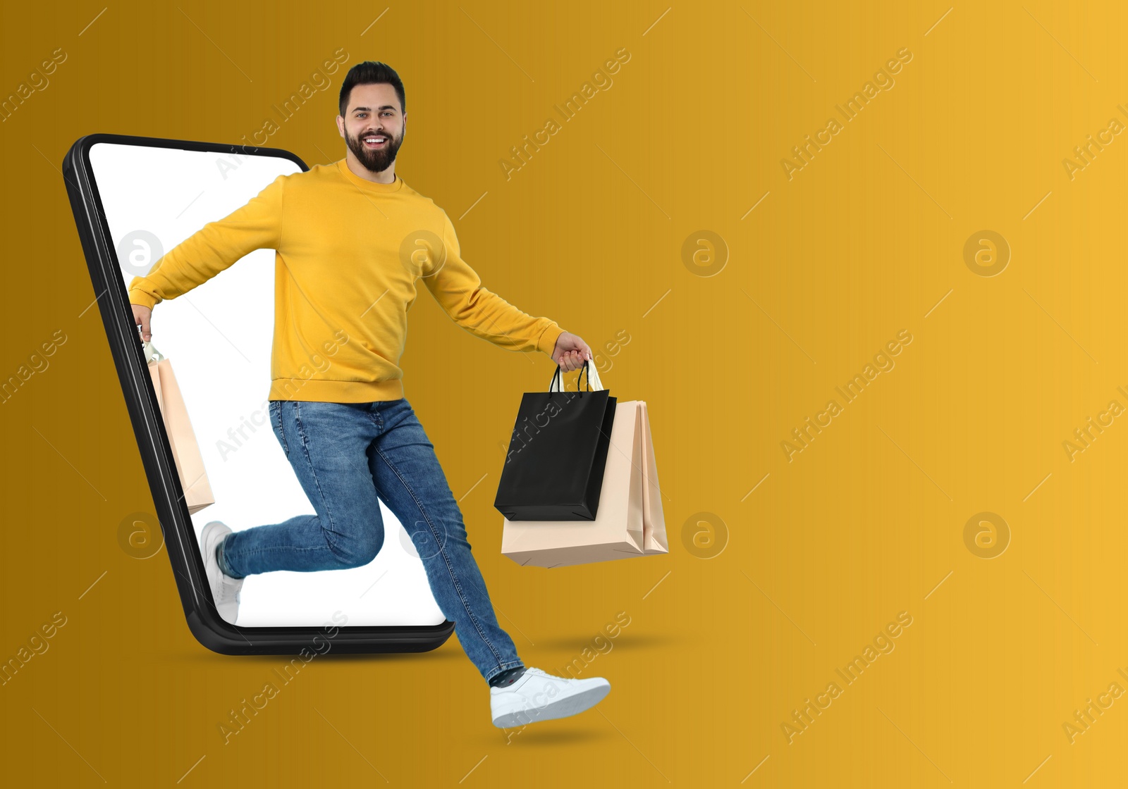 Image of Online shopping. Happy man with paper bags jumping out from smartphone on orange background, space for text