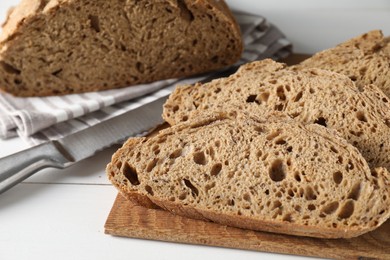 Photo of Freshly baked cut sourdough bread on white wooden table, closeup