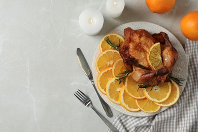 Photo of Baked chicken served with orange slices on light marble table, flat lay