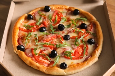 Tasty fresh pizza with olives in cardboard box, closeup