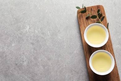 Stand with cups of freshly brewed oolong tea on grey background, top view with space for text