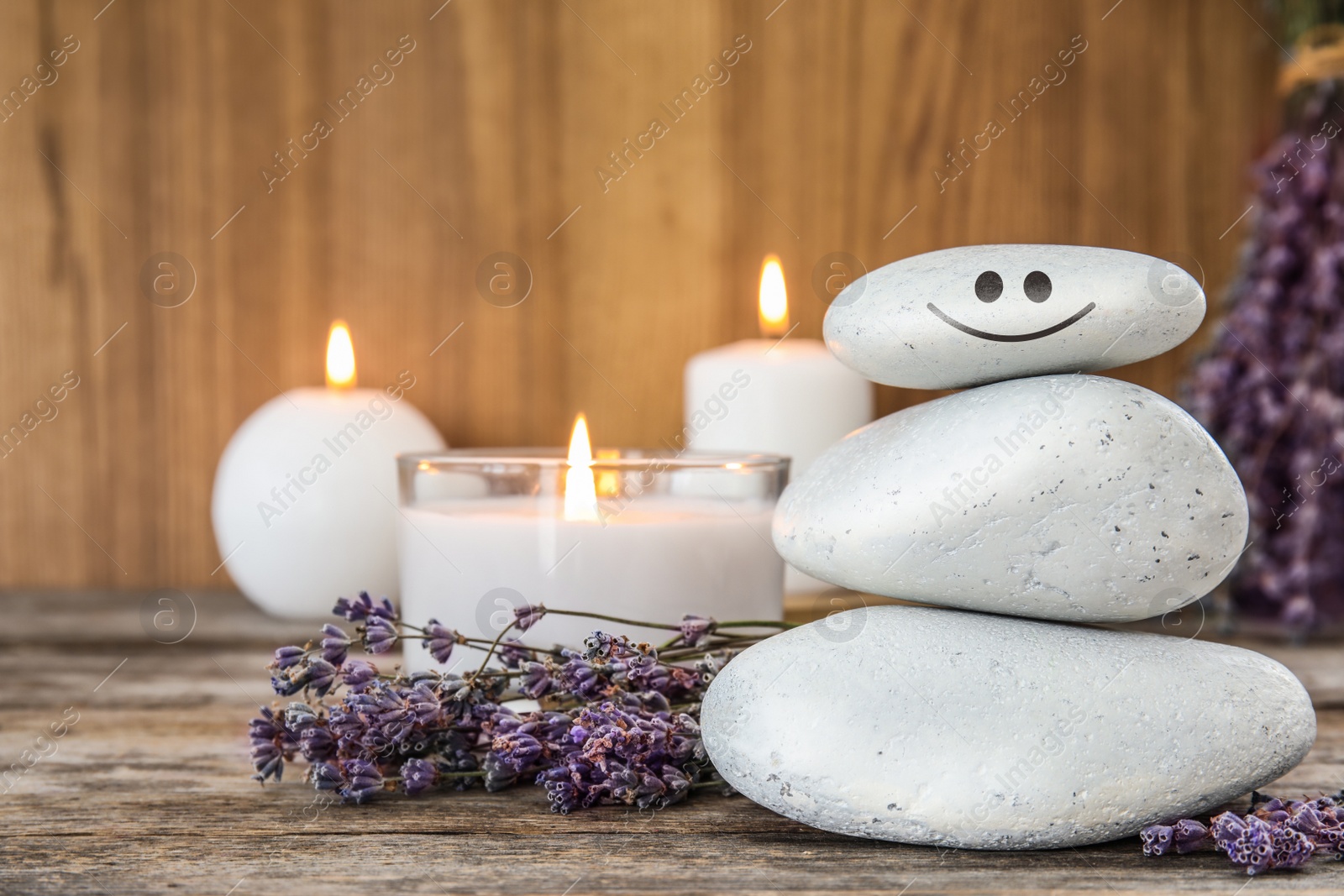 Image of Stack of stones with drawn happy face, lavender flowers and candles on wooden table. Be in harmony and enjoying your life