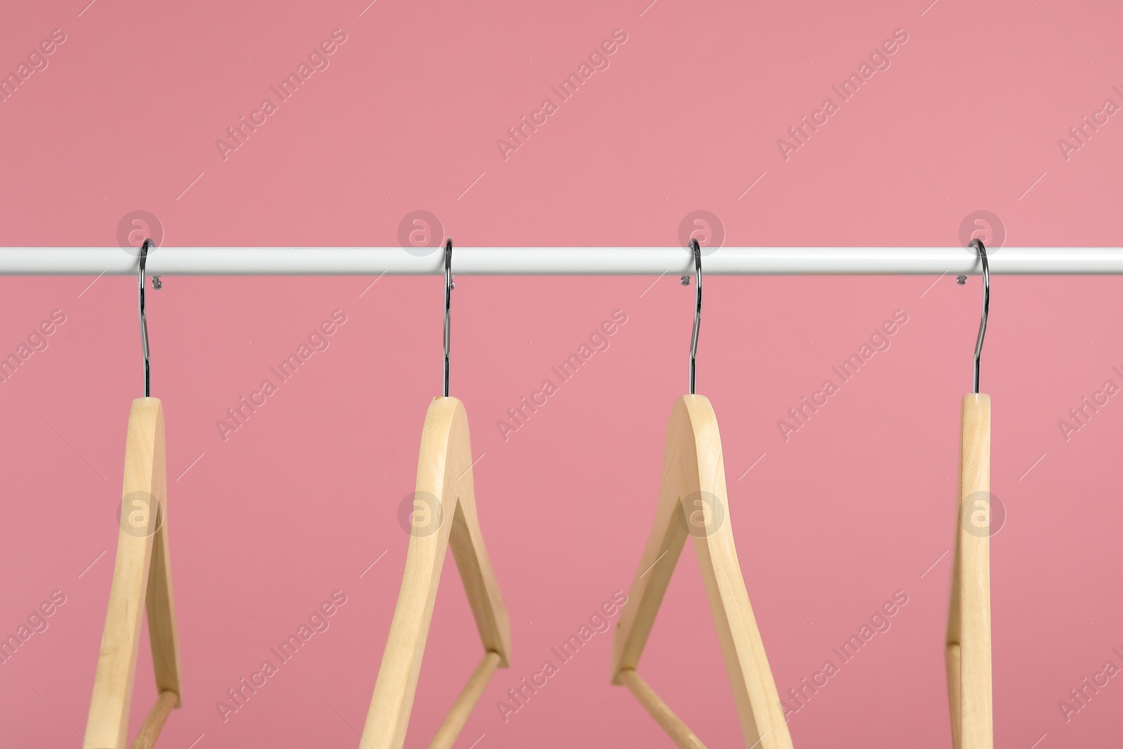 Photo of Empty clothes hangers on rack against pink background