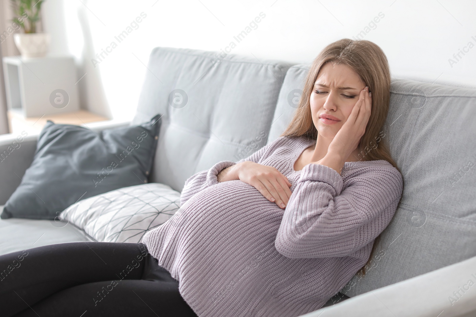 Photo of Young pregnant woman suffering from headache at home