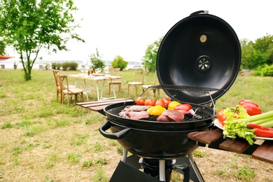 Photo of Modern grill with meat and vegetables outdoors