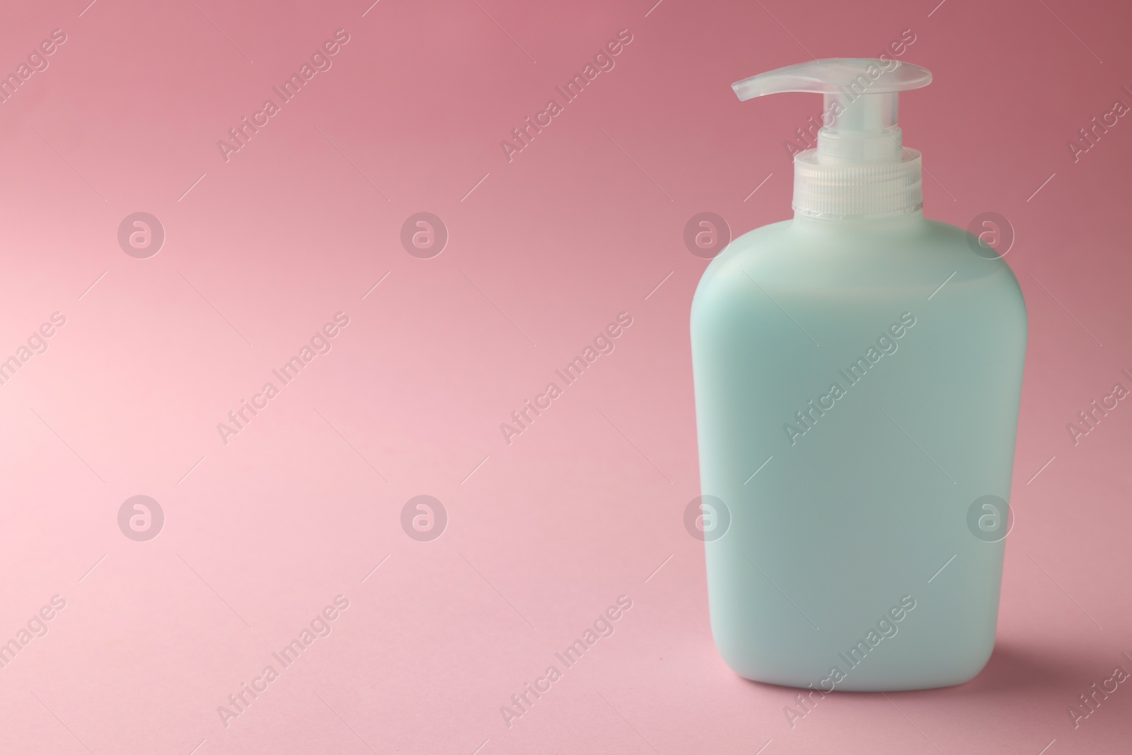 Photo of Bottle of liquid soap on pink background. Space for text