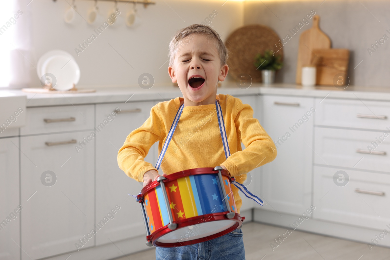 Photo of Little boy playing toy drum in kitchen