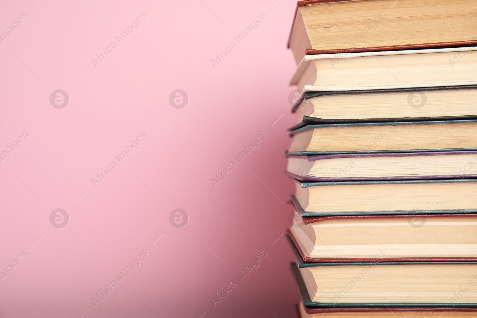 Photo of Stack of hardcover books on pink background. Space for text