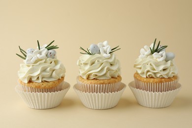 Tasty Easter cupcakes with vanilla cream on beige background