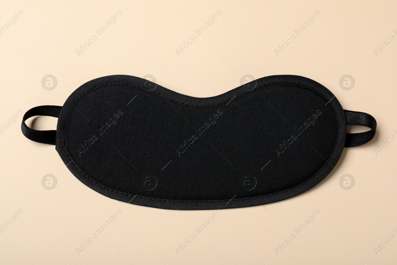 Photo of Black sleeping mask on yellow background, top view. Bedtime accessory