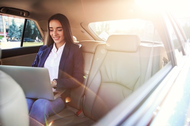 Young businesswoman with laptop in car