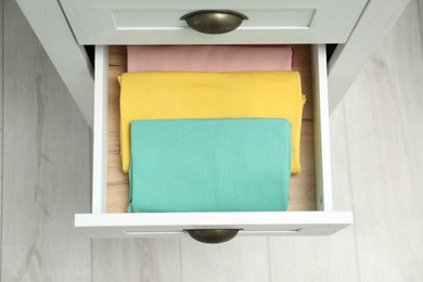 Chest of drawers with different folded clothes indoors, top view