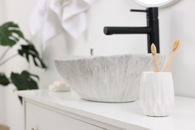 Photo of Bath accessory. Ceramic holder with toothbrushes on bathroom vanity indoors, space for text