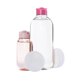 Photo of Bottles of micellar cleansing water and cotton pads on white background