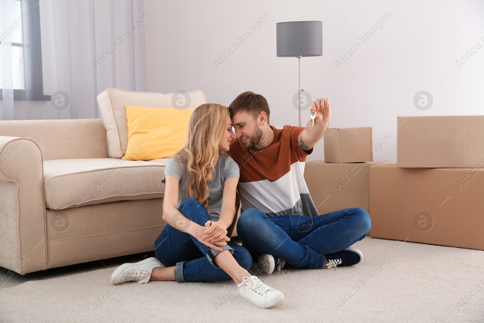 Photo of Happy young couple with key from their new house indoors