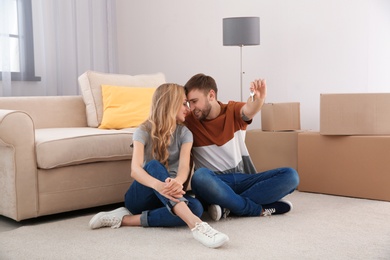 Happy young couple with key from their new house indoors