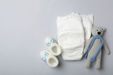 Photo of Diapers and baby accessories on light grey background, flat lay. Space for text