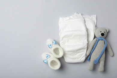 Diapers and baby accessories on light grey background, flat lay. Space for text