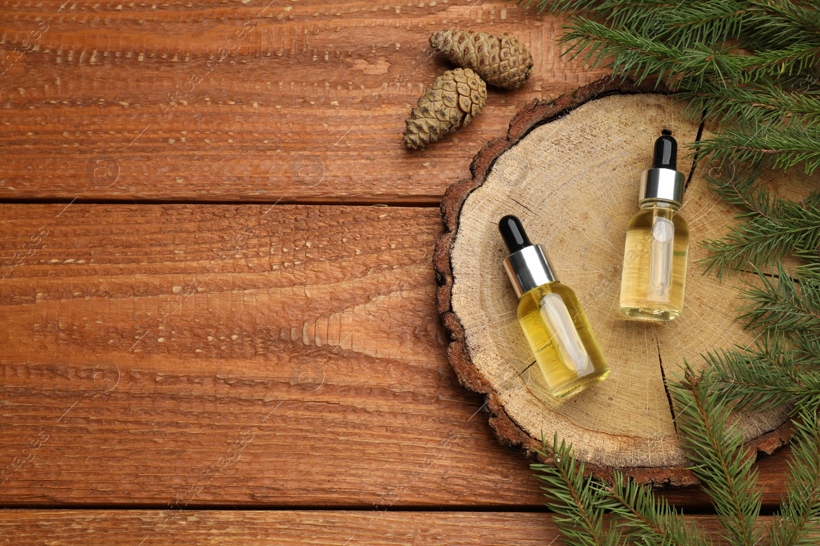 Photo of Pine essential oil, cones and branches on wooden table, flat lay. Space for text