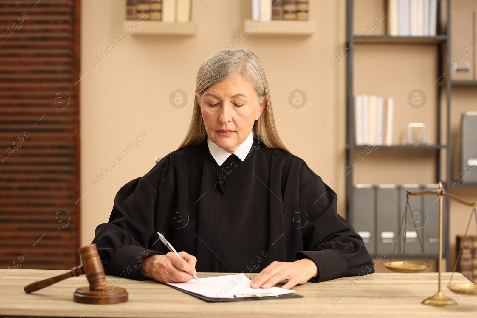 Photo of Judge in court dress working at table indoors