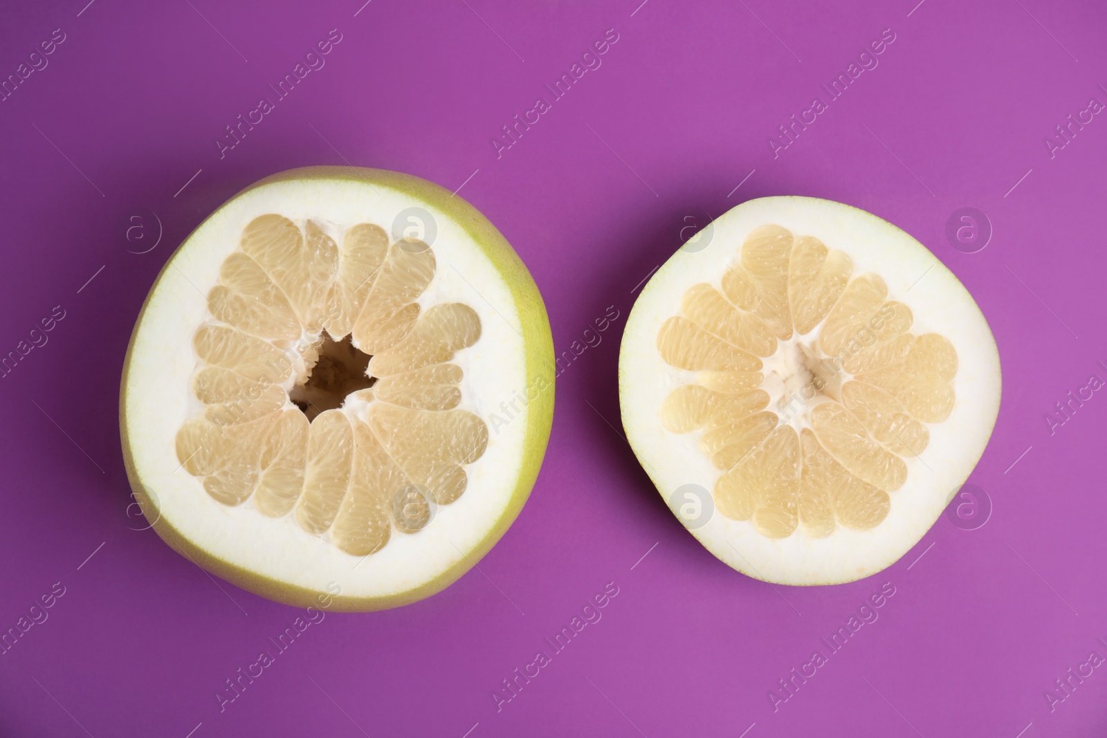 Photo of Fresh cut pomelo fruit on purple background, flat lay