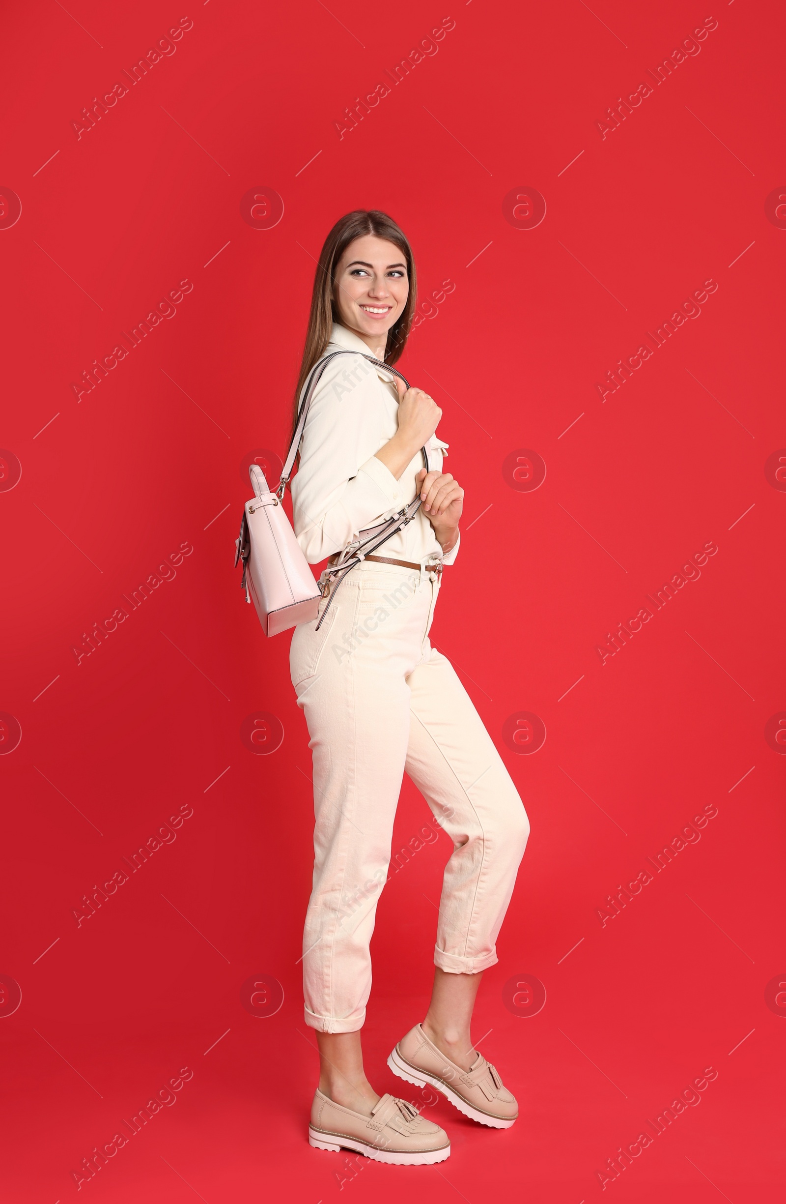 Photo of Beautiful young woman in casual outfit with stylish bag on red background