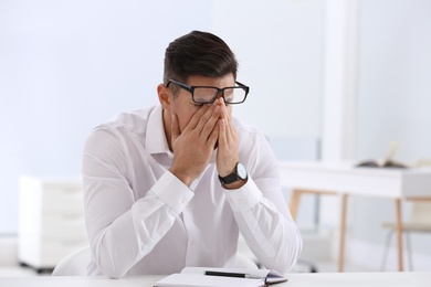 Stressed man at white table in office