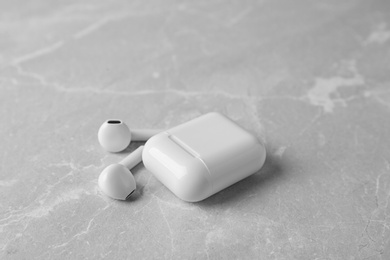 Photo of Wireless earphones and charging case on light grey marble table