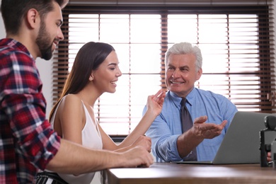 Senior notary working with young couple in office