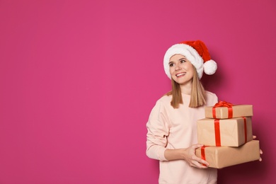 Young woman with Christmas gifts on color background