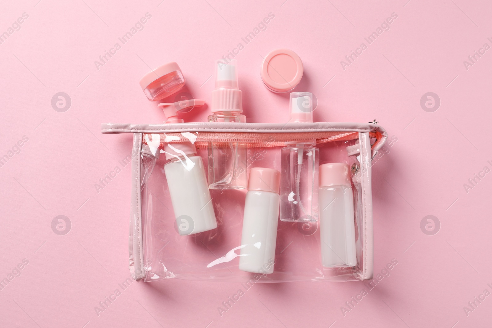 Photo of Plastic bag with cosmetic travel kit on pink background, flat lay. Bath accessories