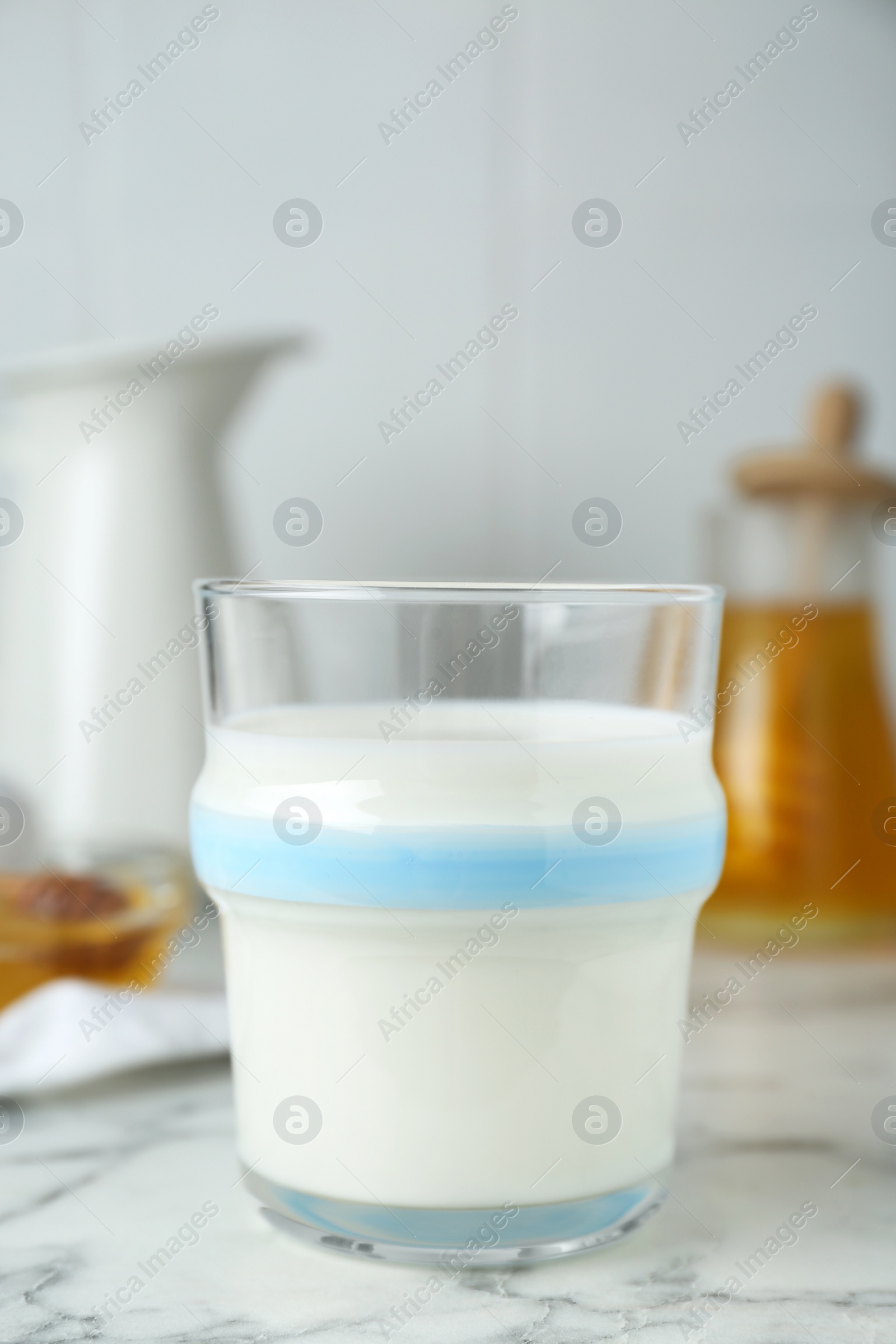 Photo of Delicious milk and honey on white marble table