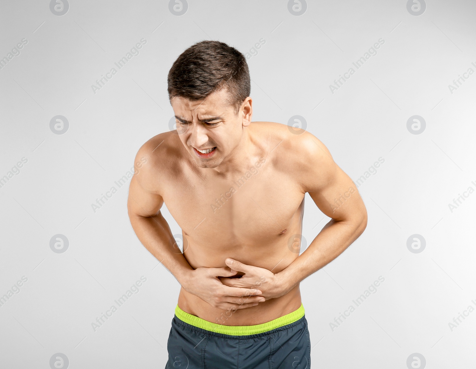 Photo of Young man suffering from abdominal pain on light background