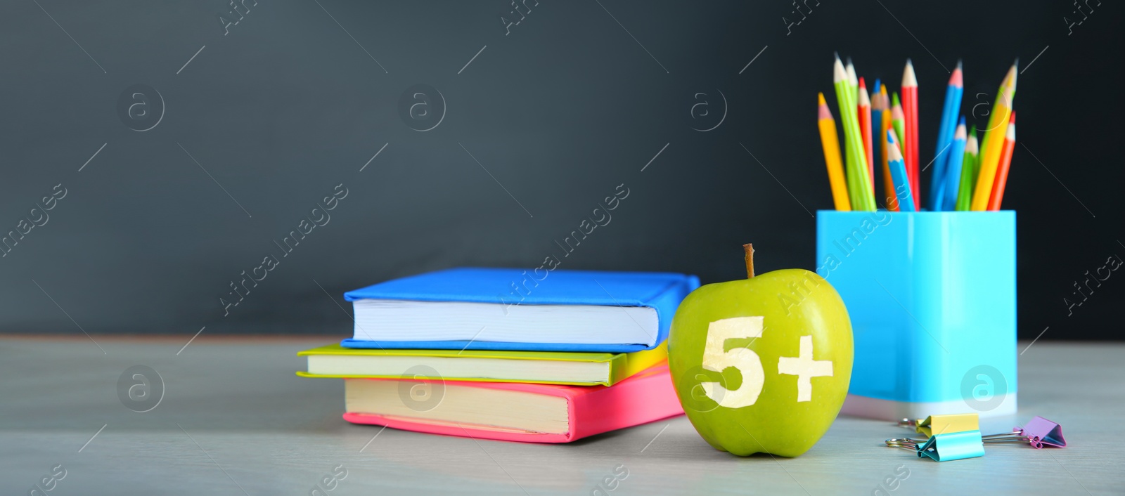 Image of Apple with carved number five and plus symbol as grade. School stationery on white table in classroom. Banner design with space for text