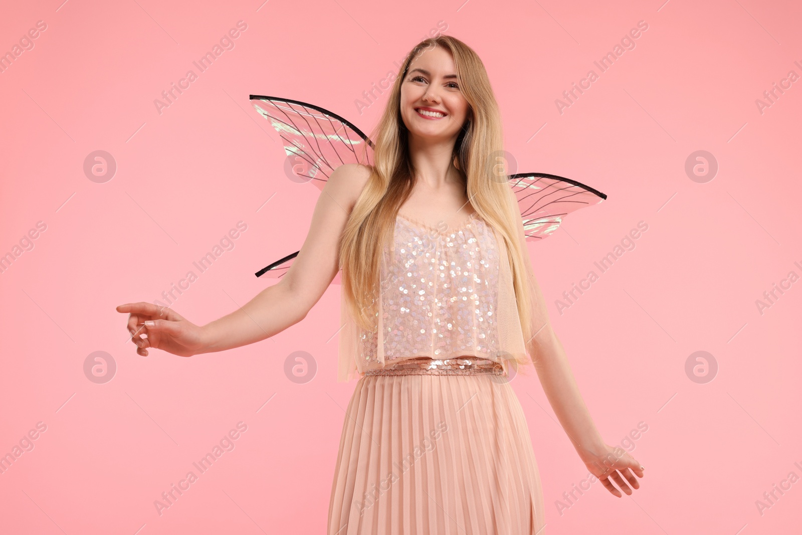 Photo of Beautiful girl in fairy costume with wings on pink background