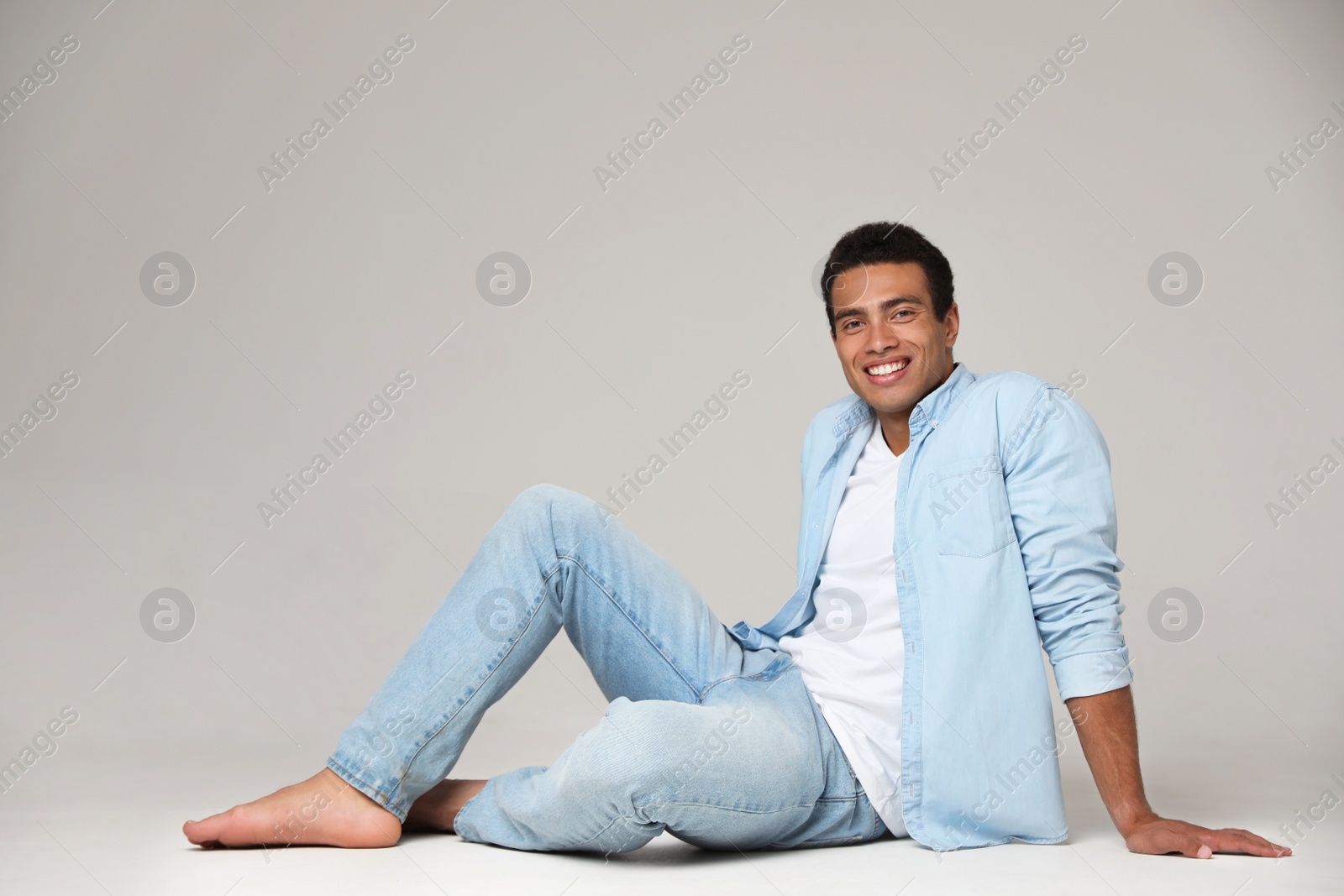 Photo of Handsome young African-American man sitting on light background