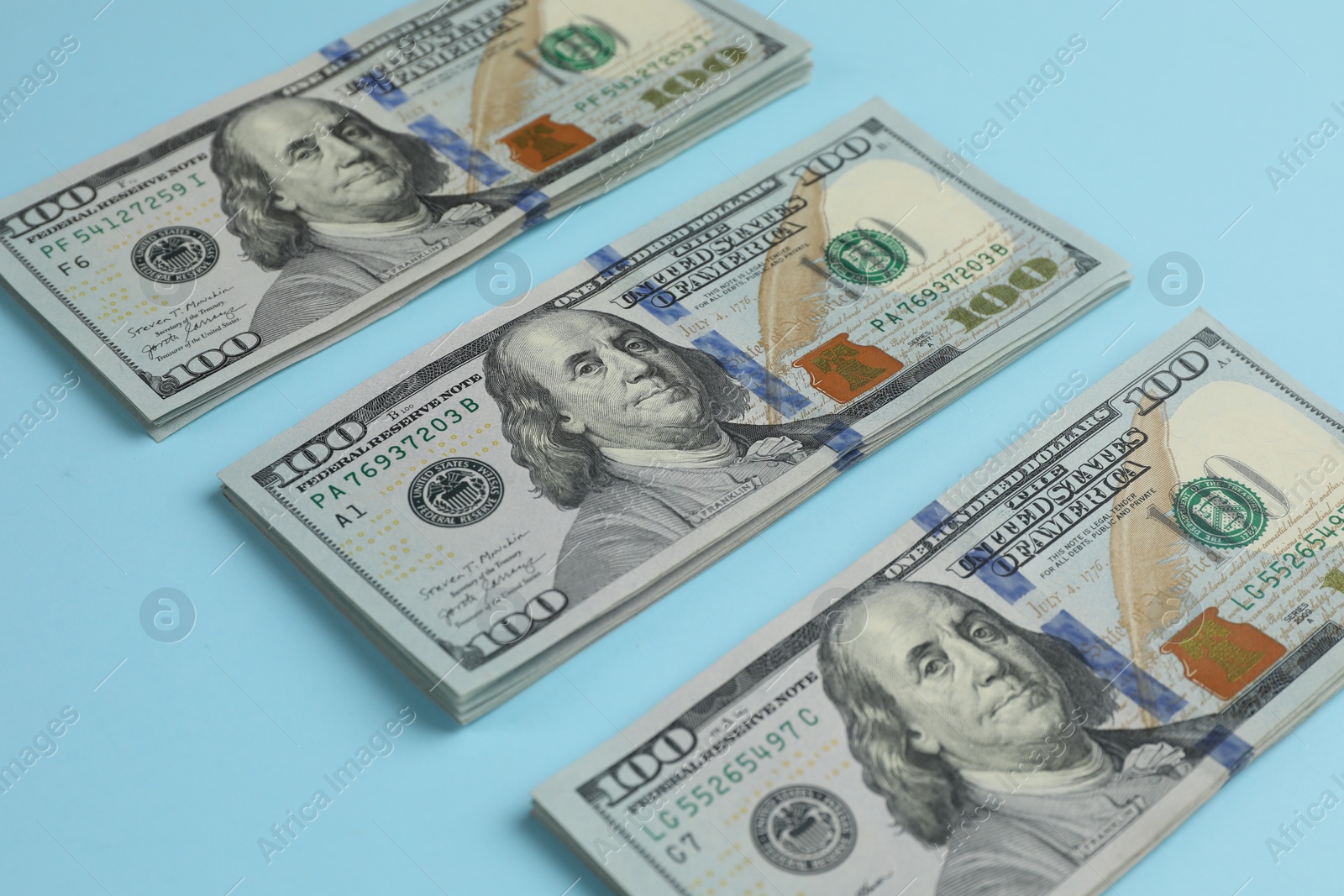 Photo of Money exchange. Dollar banknotes on light blue background, closeup