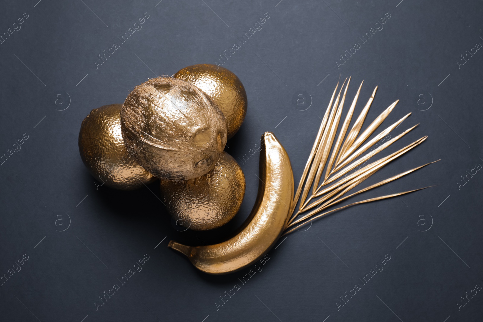 Photo of Golden fruits, coconut and palm leaf on black background, flat lay