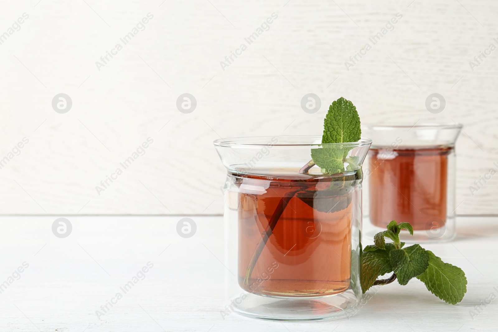 Photo of Glass cups with tasty tea on white table. Space for text