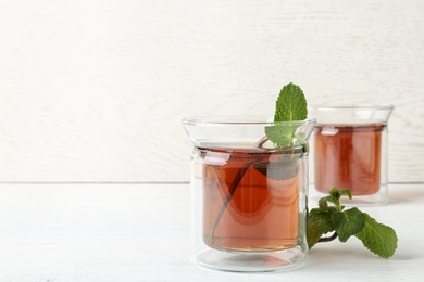 Photo of Glass cups with tasty tea on white table. Space for text