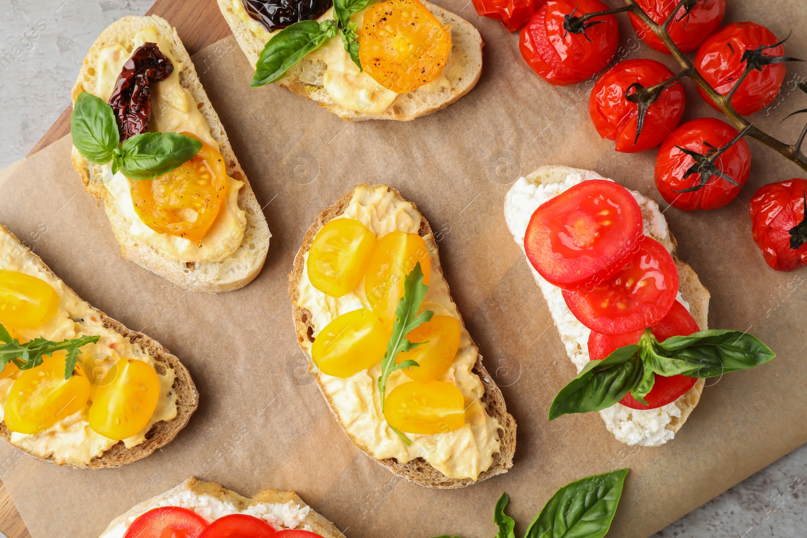 Photo of Tasty fresh tomato bruschettas on parchment, flat lay