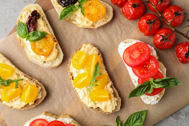 Tasty fresh tomato bruschettas on parchment, flat lay