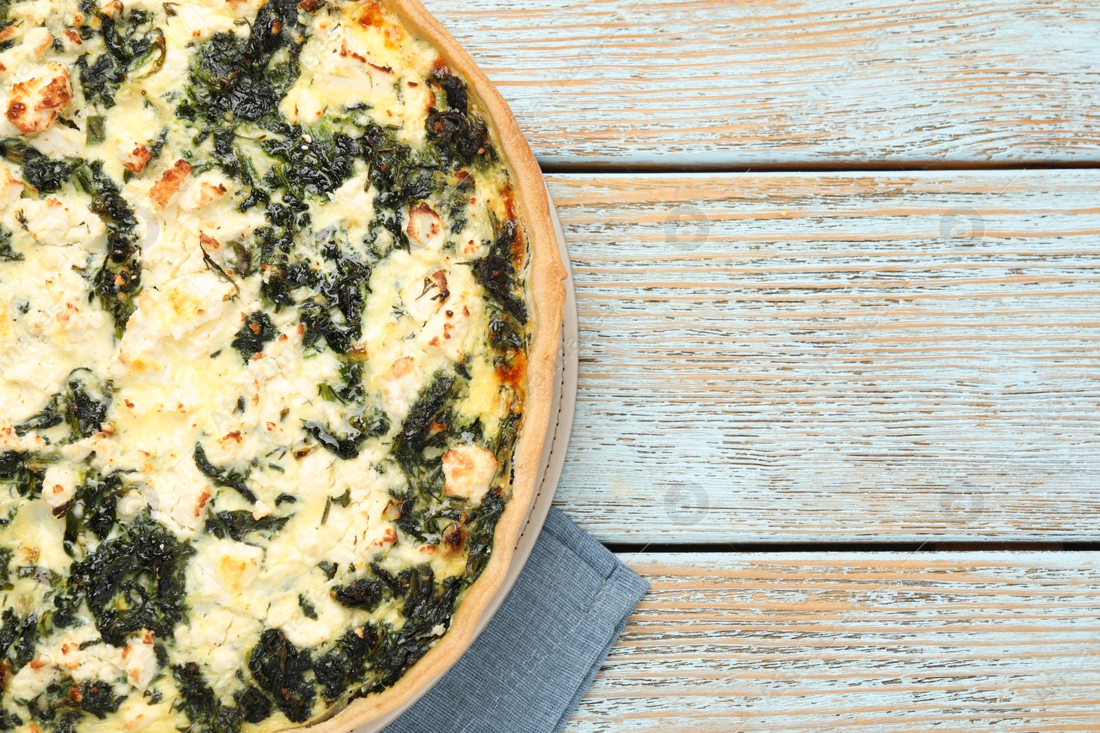 Photo of Delicious homemade spinach quiche on rustic wooden table, top view. Space for text